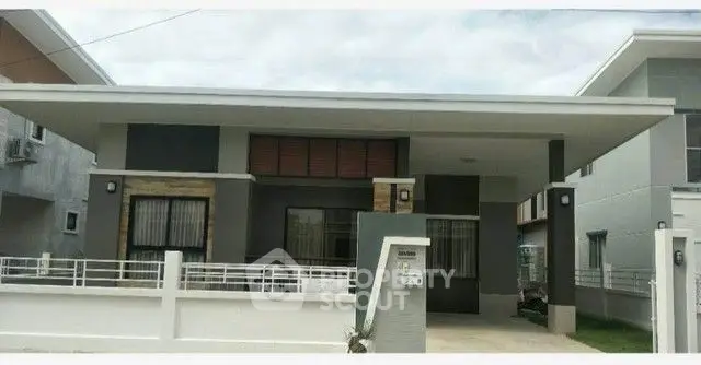 Modern single-story house with sleek design and spacious driveway in a suburban neighborhood.