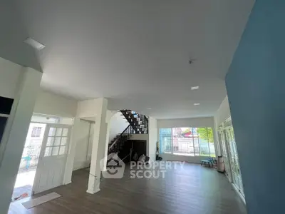 Spacious open-plan living room with large windows and modern staircase