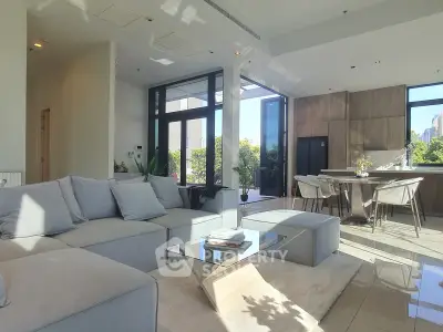 Luxurious modern living room with open kitchen and large windows offering stunning city views.