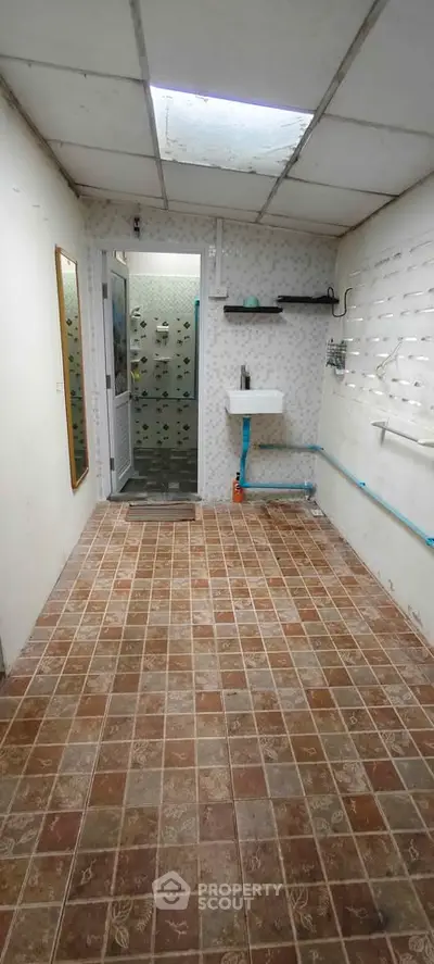 Spacious bathroom with tiled floor and wall-mounted sink, featuring a skylight for natural lighting.
