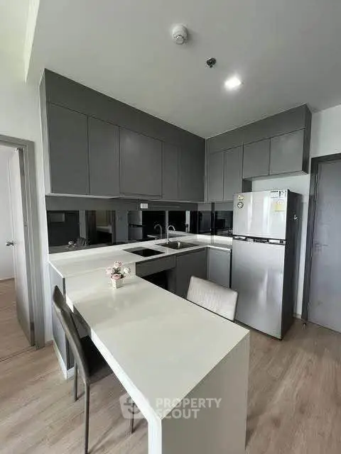 Modern kitchen with sleek gray cabinets and integrated dining area in a stylish apartment.