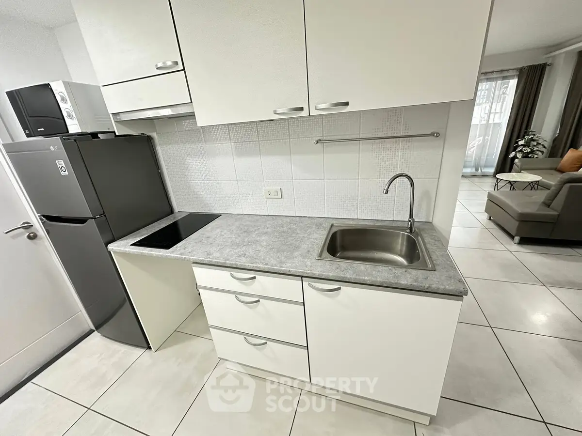 Modern kitchen with sleek cabinetry and stainless steel appliances in open layout apartment.