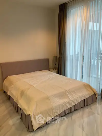 Spacious bedroom with elegant curtains and natural light, perfect for relaxation and comfort.