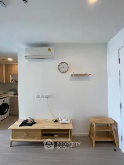 Modern living room with air conditioning, wooden furniture, and a washing machine in view.