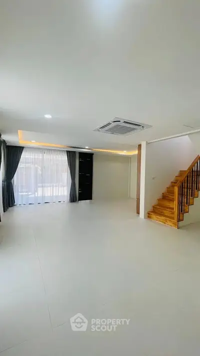 Spacious modern living room with elegant staircase and large windows