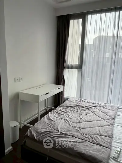 Cozy bedroom with modern furnishings and large window for natural light.