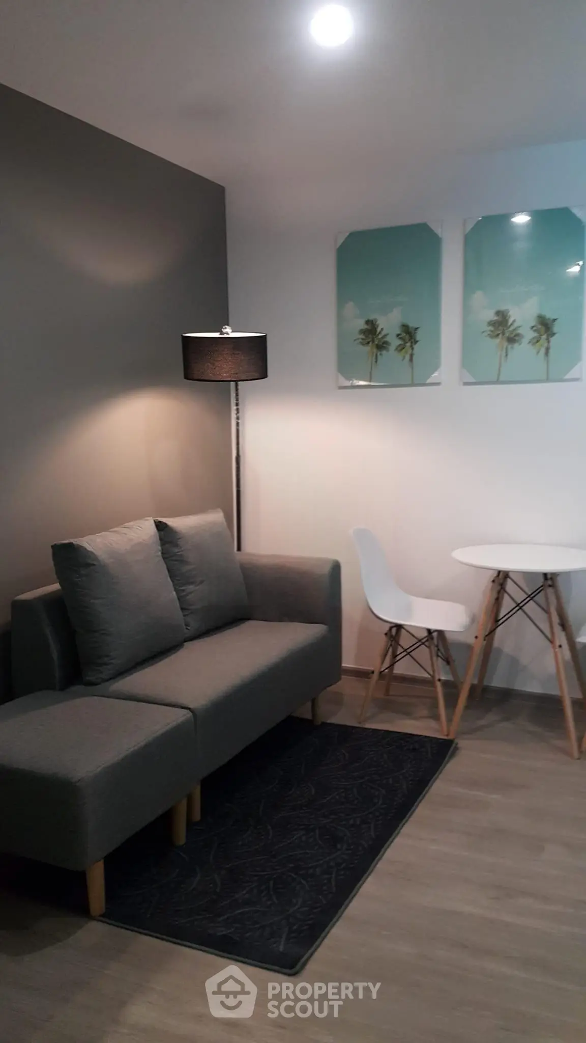 Modern living room with stylish gray sofa, chic floor lamp, and minimalist dining set.