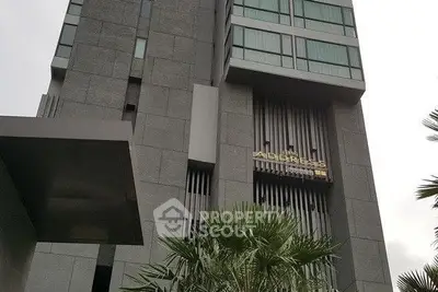 Modern high-rise building exterior with sleek design and lush greenery.