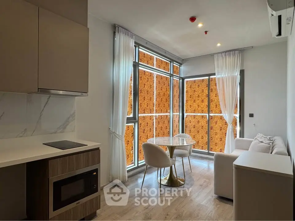 Modern living room with open kitchen and large windows in a stylish apartment.