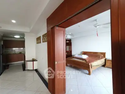 Spacious bedroom with wooden accents and adjacent kitchen area