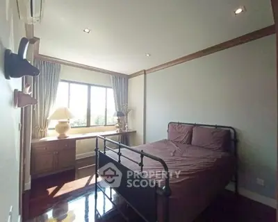 Cozy bedroom with natural light and elegant decor, featuring a stylish bed and large window.