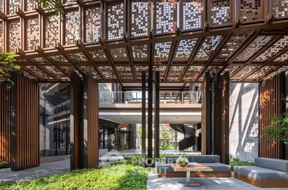 Stunning modern building entrance with intricate metalwork and lush greenery.