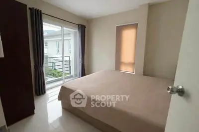 Cozy bedroom with large window and balcony access in modern apartment.