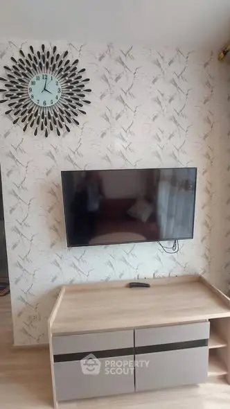 Modern living room with wall-mounted TV and stylish clock on patterned wallpaper.