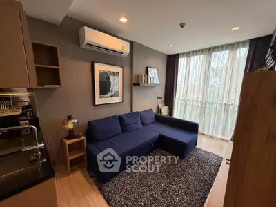 Modern living room with blue sofa, stylish decor, and large windows for natural light.