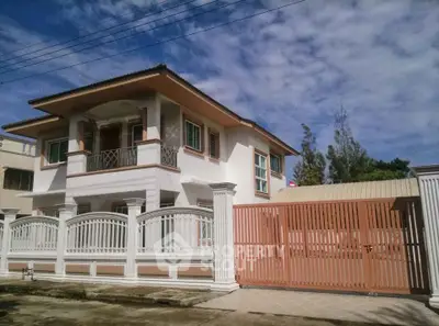 Elegant two-story house with gated entrance and balcony under a clear blue sky.