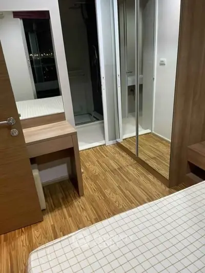 Cozy bedroom with wooden flooring and mirrored closet doors, offering a modern and functional living space.