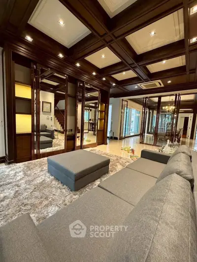 Luxurious living room with plush gray sofa and elegant wooden ceiling design.