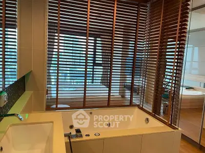 Luxurious bathroom with modern bathtub and city view through wooden blinds.