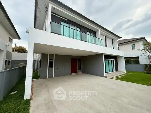 Modern two-story house with spacious driveway and balcony in a serene neighborhood.