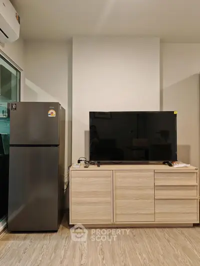 Modern living room with sleek TV stand and refrigerator, perfect for urban living.