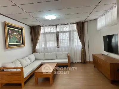 Spacious living room with modern wooden furniture and large window for natural light.