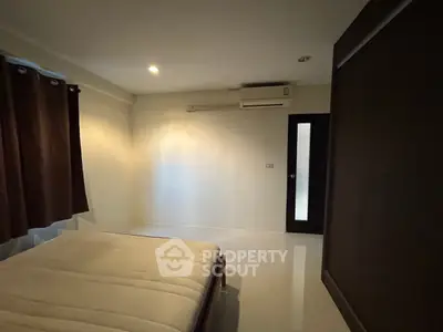 Spacious bedroom with minimalist design and air conditioning in modern apartment.