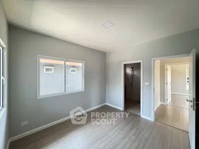 Spacious empty room with large windows and modern flooring, perfect for customization.