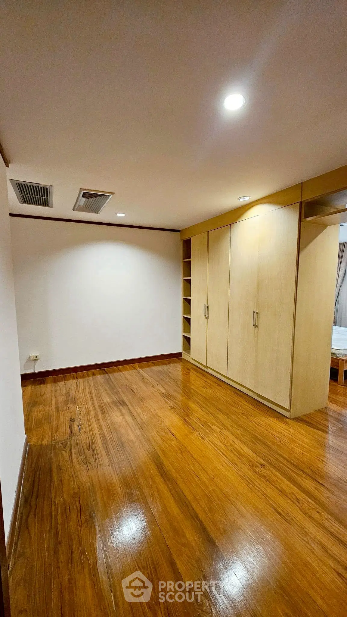 Spacious bedroom with wooden flooring and built-in wardrobe