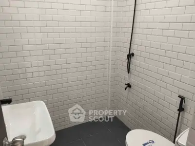 Modern minimalist bathroom with white subway tiles and sleek fixtures.