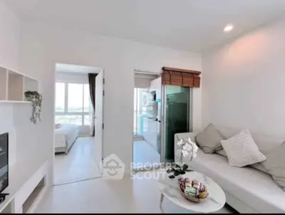 Modern living room with cozy sofa, open layout to kitchen and bedroom, bright natural light.