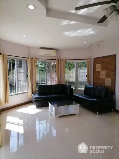 Spacious living room with modern black sofas and large windows