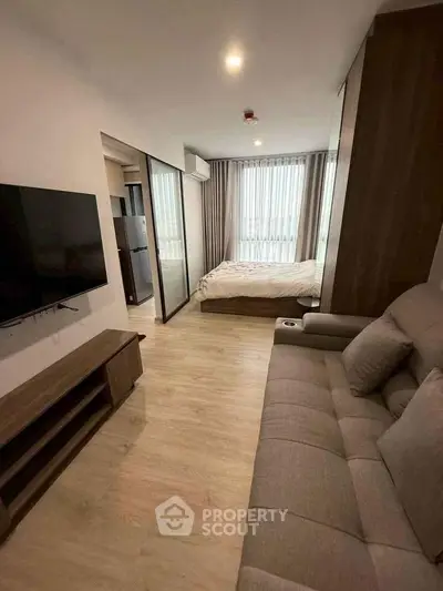 Modern studio apartment with cozy living area and bedroom, featuring sleek furniture and natural light.