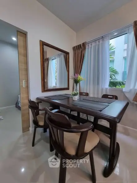 Elegant dining area with wooden table and chairs, large mirror, and natural light from window.
