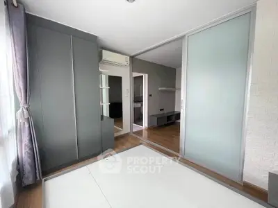 Spacious bedroom with modern wardrobe and large window for natural light.