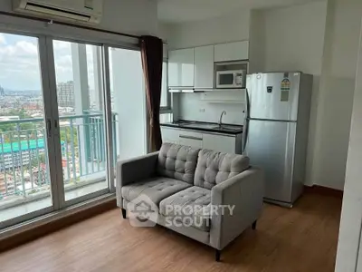 Modern apartment with balcony view, cozy living area, and compact kitchen featuring fridge and microwave.