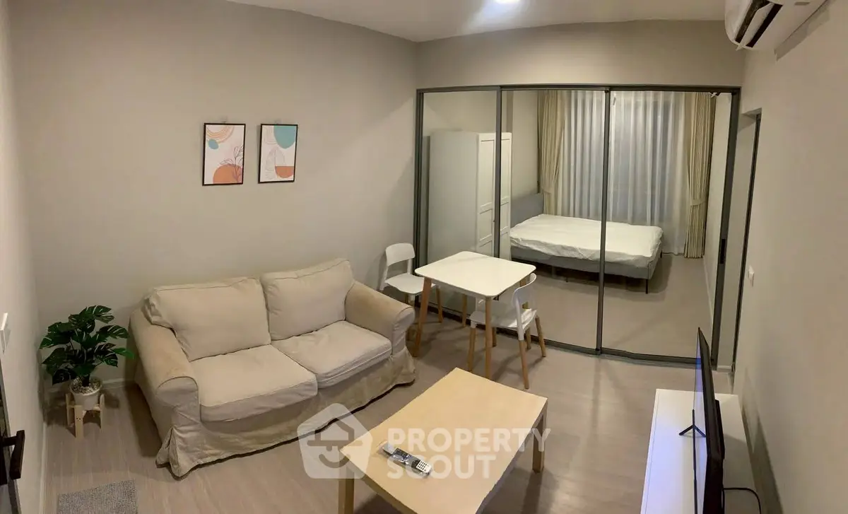Modern studio apartment with glass partition, cozy living area, and minimalist decor.