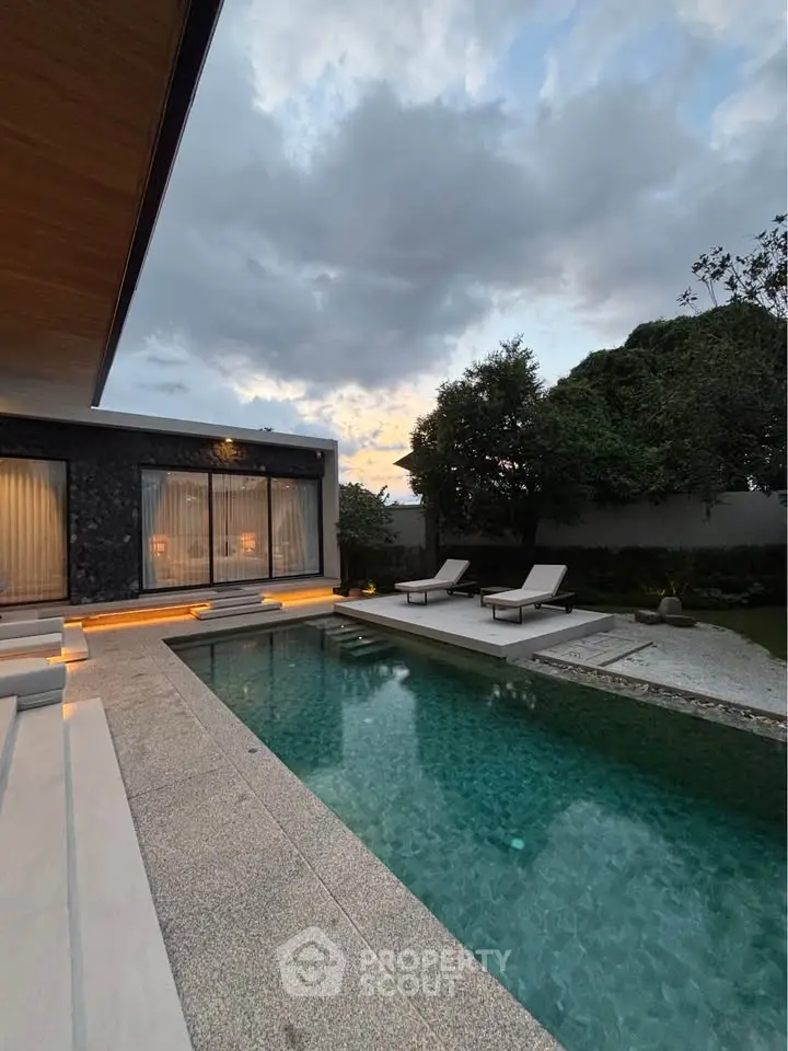 Luxurious modern home with stunning pool and elegant outdoor area at sunset.