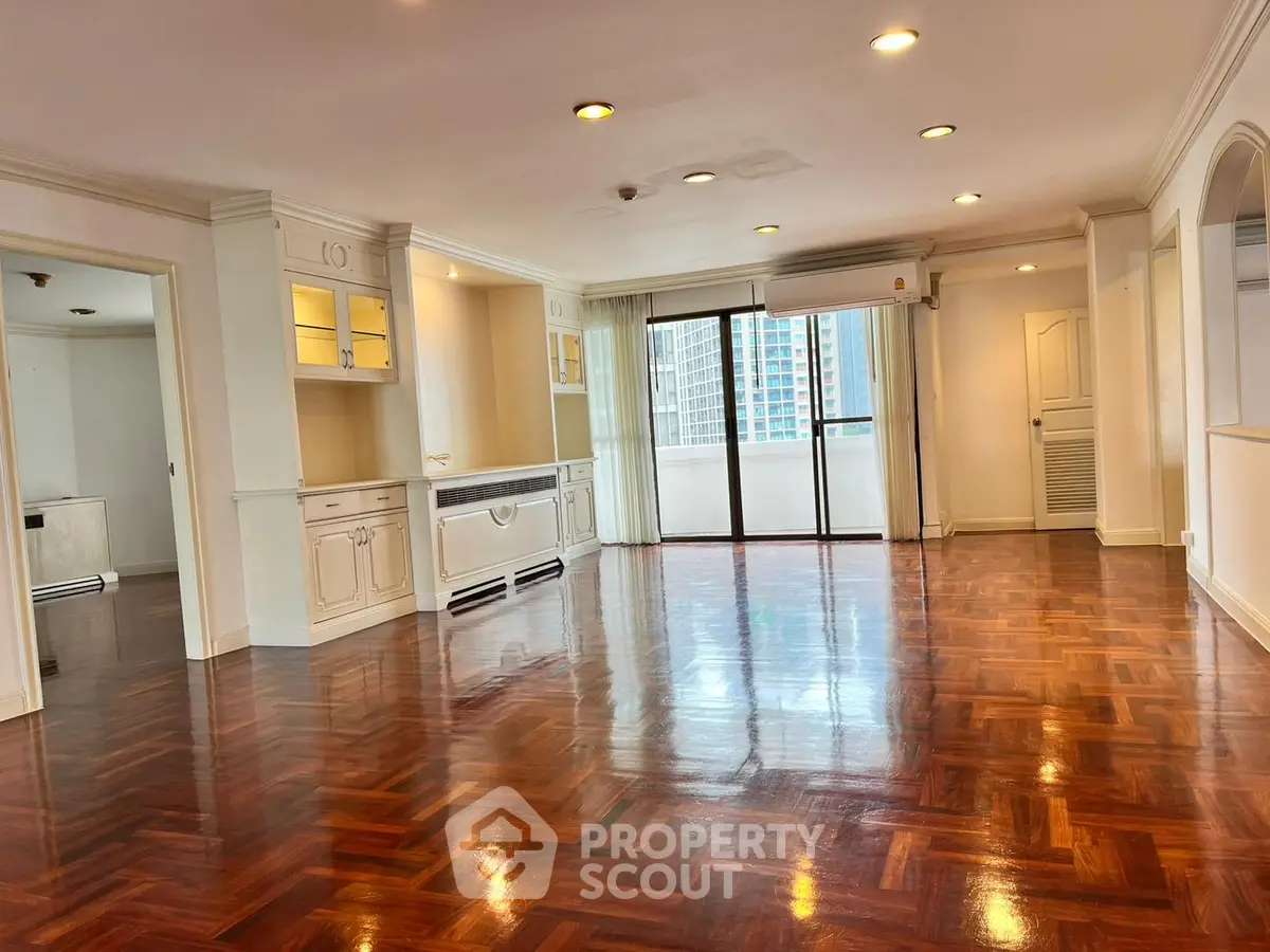 Spacious living room with polished wooden floors and large windows in a high-rise apartment.