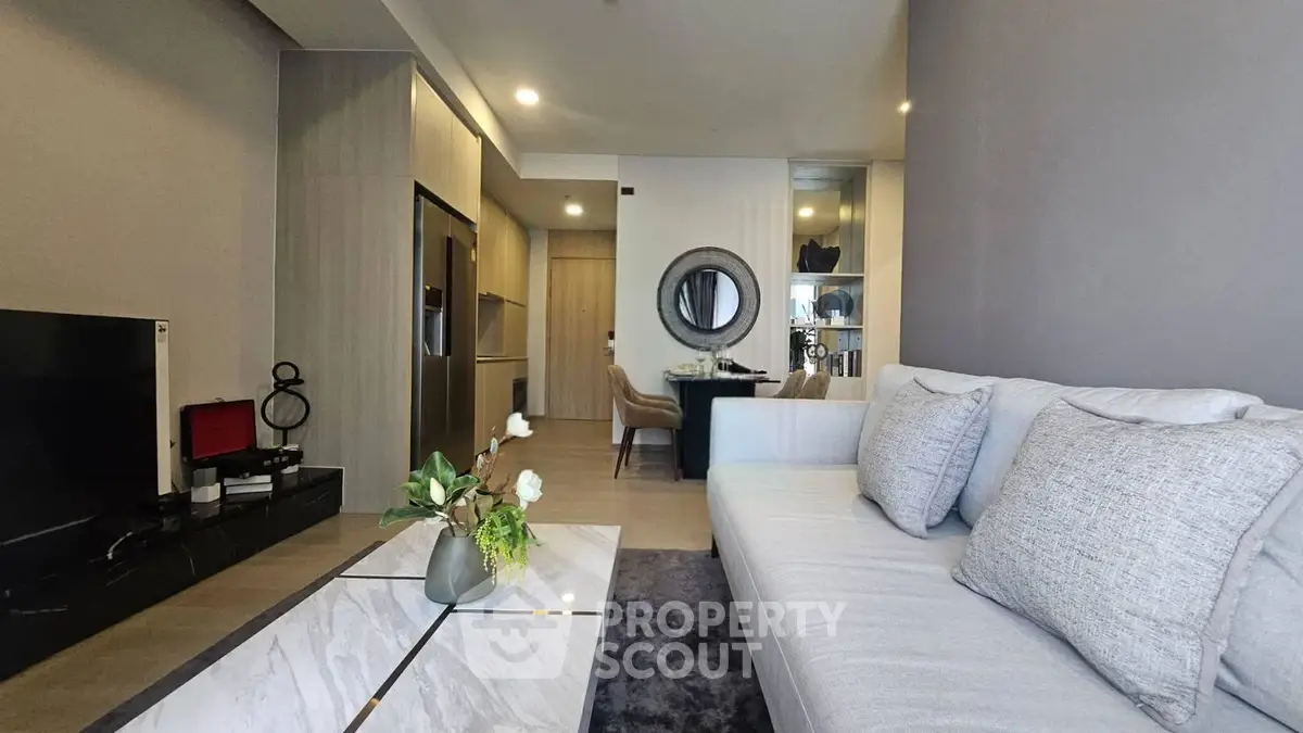 Modern living room with elegant decor and open layout, featuring a cozy sofa and stylish dining area.