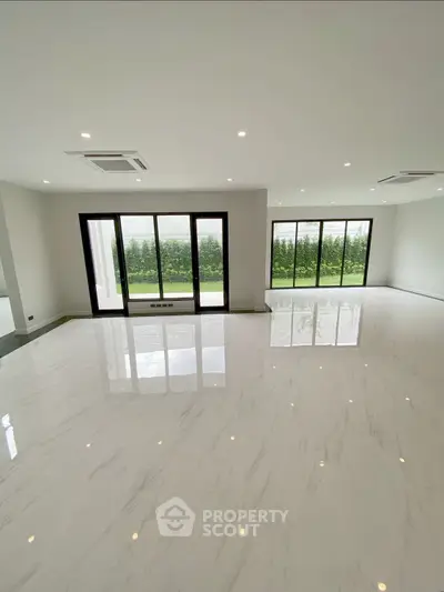Spacious modern living room with large windows and glossy marble floors.