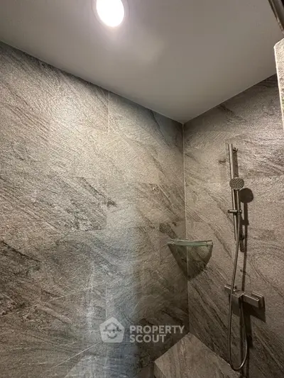 Modern bathroom with sleek gray stone tiles and rainfall showerhead