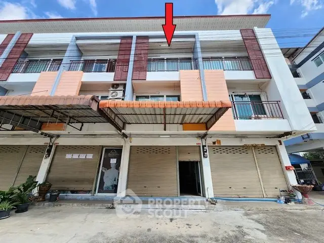 Modern multi-story building with closed storefronts and residential balconies, ideal for mixed-use investment.