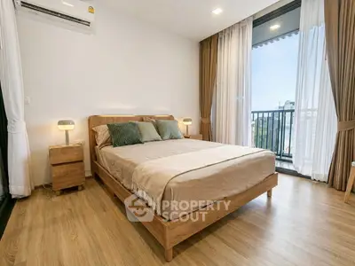 Modern bedroom with wooden flooring and balcony view in a stylish apartment.