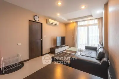 Modern living room with sleek leather sofa and large window offering natural light.
