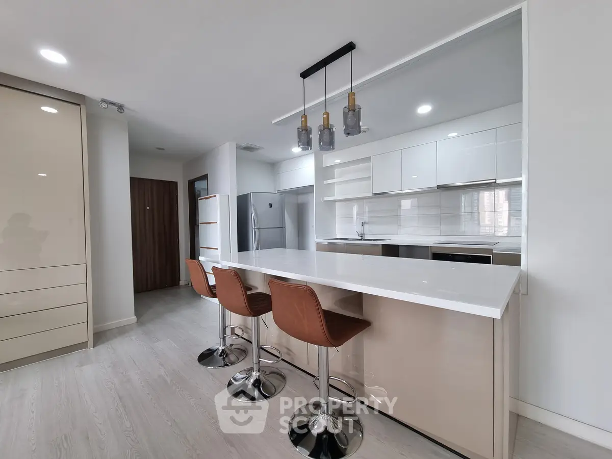 Modern kitchen with sleek design, featuring island seating and stainless steel appliances.