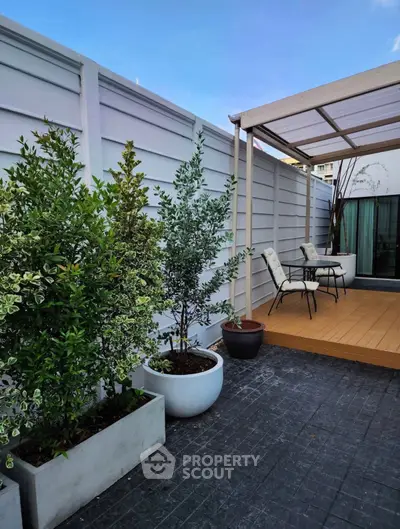 Charming outdoor patio with modern decking and lush potted plants, perfect for relaxation and entertaining.