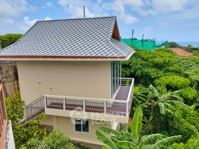Charming two-story house with balcony nestled in lush greenery and scenic views.