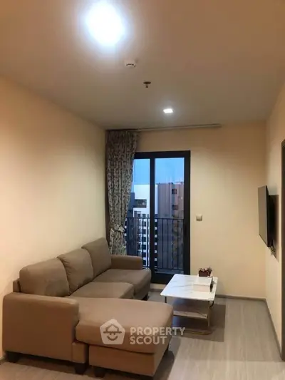 Modern living room with cozy sofa and balcony view in urban apartment.