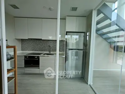 Modern kitchen with sleek cabinetry and stainless steel appliances in a stylish apartment.